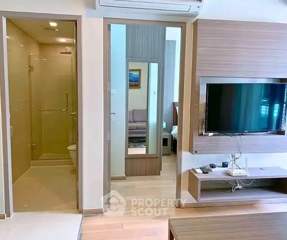 Modern living room with TV and view into bathroom, showcasing sleek design and wooden accents.