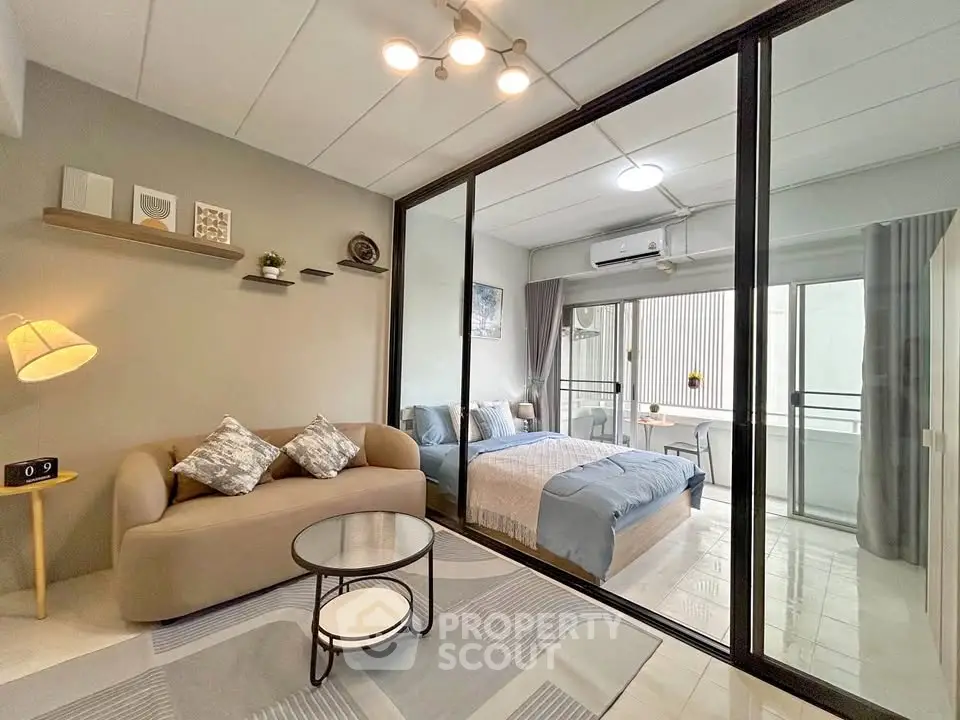 Modern studio apartment with glass partition, cozy living area, and stylish decor.