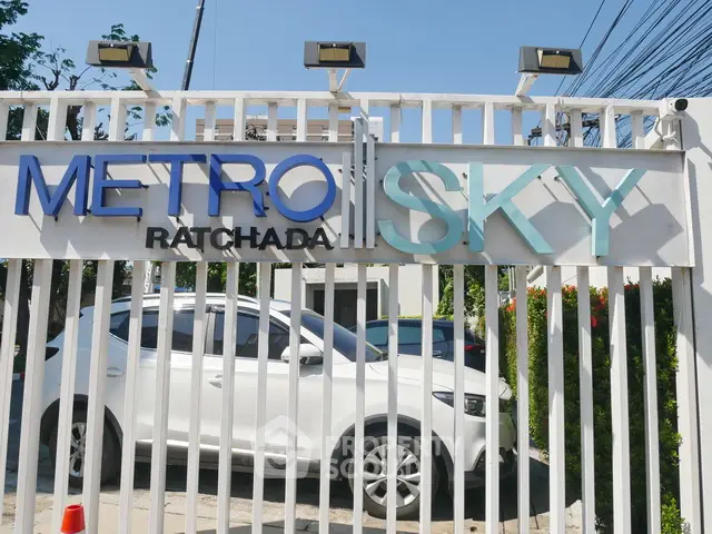 Modern Metro Sky Ratchada entrance with sleek design and white car parked outside.