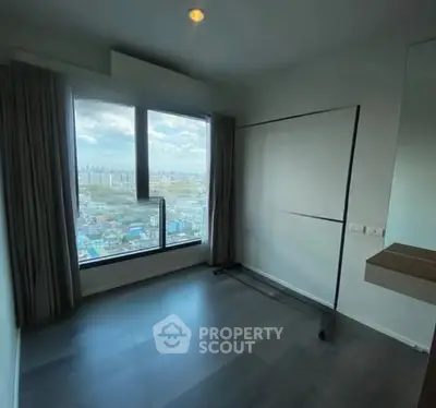 Spacious room with large window offering stunning city view.