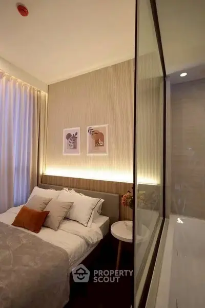 Cozy bedroom with modern decor and soft lighting, featuring a glass partition and elegant wall art.
