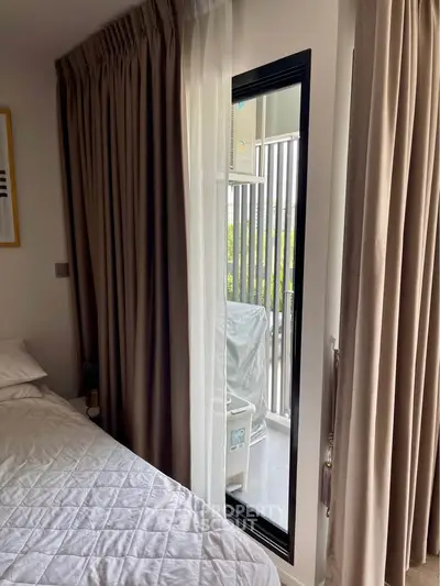 Cozy bedroom with elegant curtains and a glimpse of a balcony, perfect for urban living.