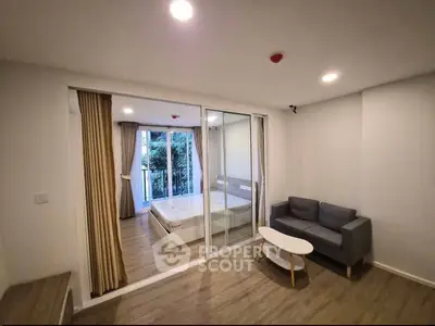 Modern apartment with cozy living room and bedroom, featuring sliding glass doors and stylish furnishings.