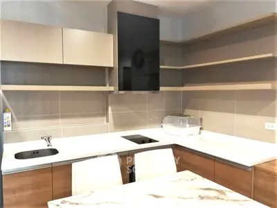 Modern kitchen with sleek cabinetry and built-in appliances, featuring a stylish marble countertop.