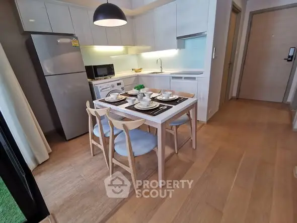 Modern kitchen with dining area featuring sleek appliances and stylish wooden furniture.