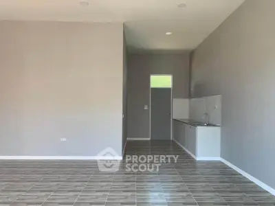 Spacious open-plan living area with modern kitchen and sleek tile flooring.