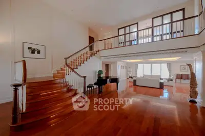 Luxurious open living room with grand staircase and elegant wooden flooring