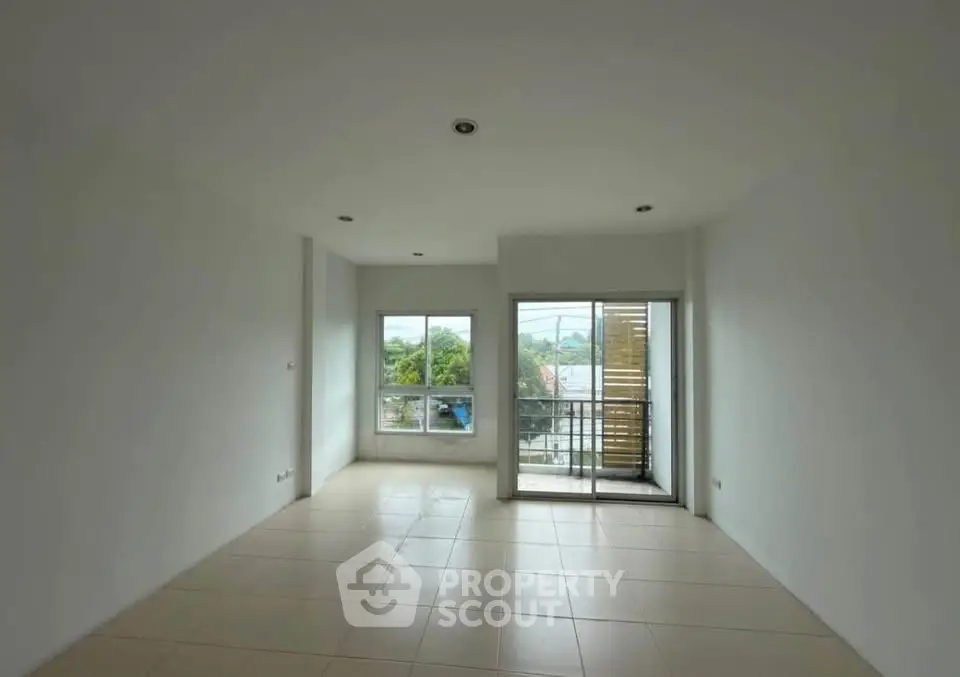 Spacious living room with large windows and balcony access, offering natural light and outdoor views.