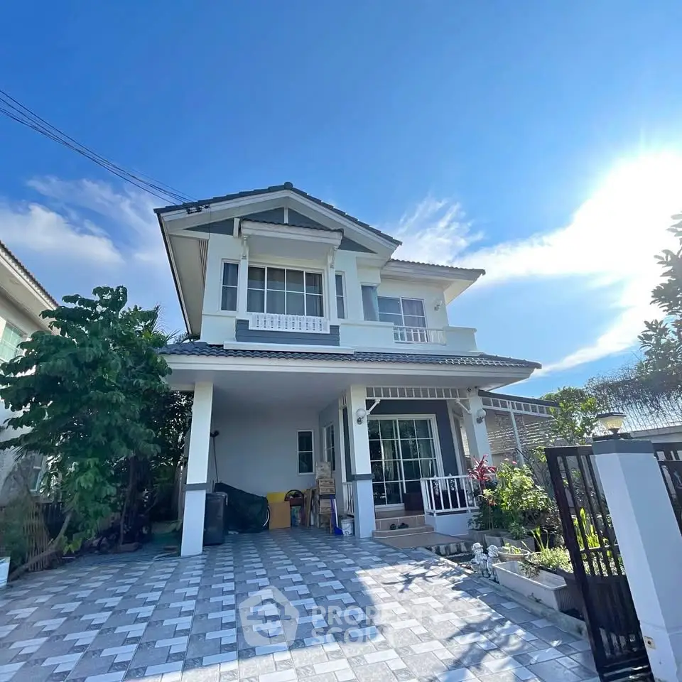 Charming two-story house with spacious driveway and lush greenery under a clear blue sky.