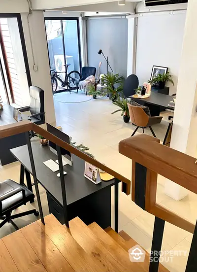 Spacious and modern open-plan living area with abundant natural light, featuring a stylish home office setup, comfortable seating, and a cozy balcony with greenery.