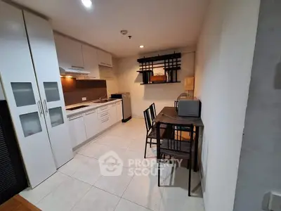 Modern kitchen with dining area, featuring sleek cabinetry and compact design.