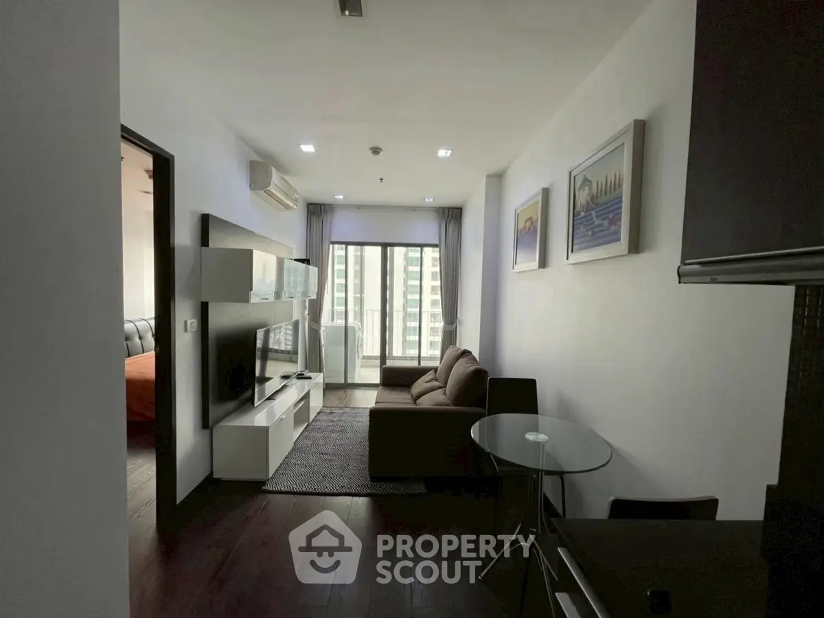 Modern living room with stylish furniture and large window view in urban apartment.