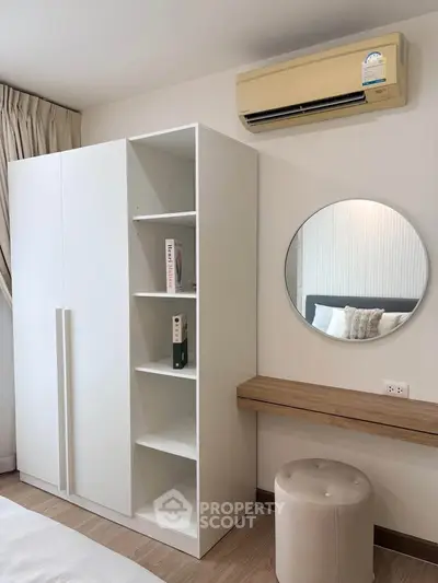 Modern bedroom with sleek white wardrobe, round mirror, and air conditioning unit for ultimate comfort.