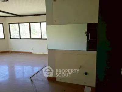 Spacious empty room with large windows and wooden flooring, ideal for customization.