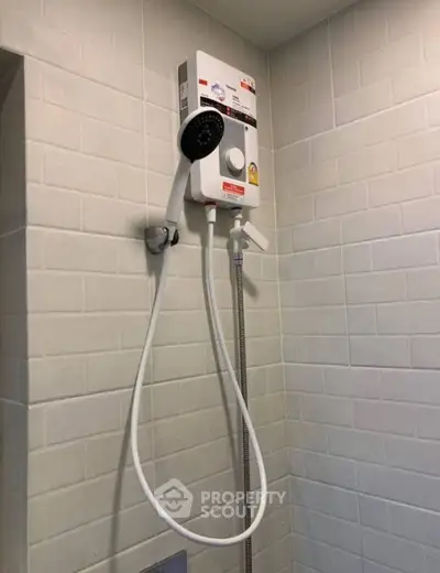 Modern bathroom with electric shower heater and sleek white tiles.