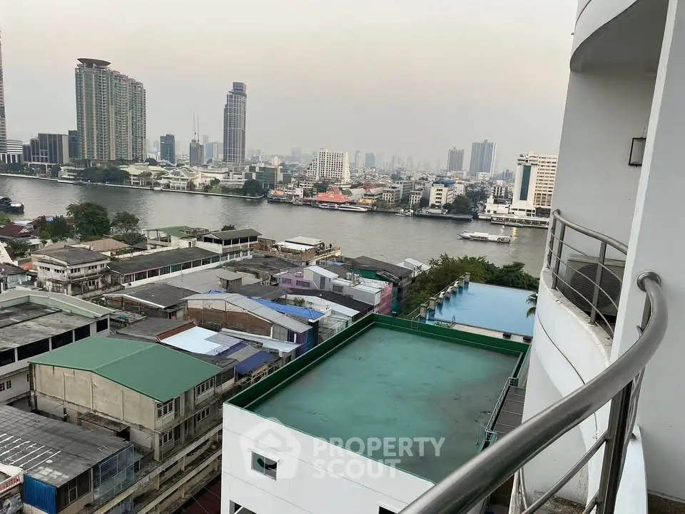 Stunning river view from high-rise balcony overlooking city skyline and waterfront buildings.