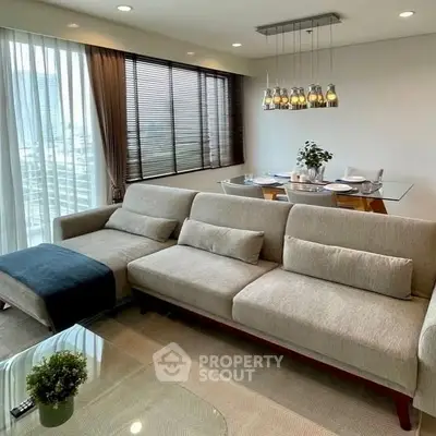 Modern living room with large sofa and dining area, featuring city view.