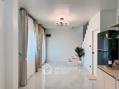 Modern minimalist interior with sleek staircase and stylish kitchen area.