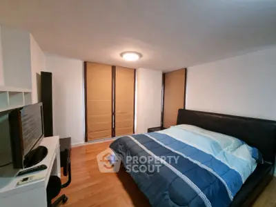 Cozy bedroom with modern furnishings and ample natural light from large windows.