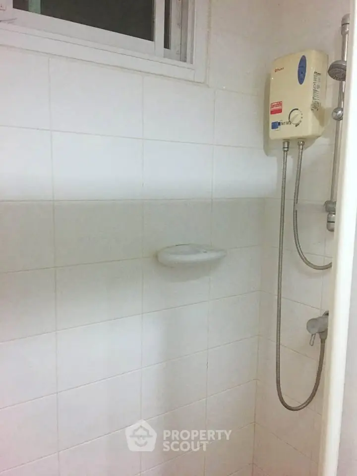 Compact bathroom with shower and water heater, ideal for small spaces.