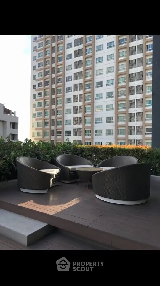 Modern outdoor seating area with stylish chairs and lush greenery in a high-rise building setting.