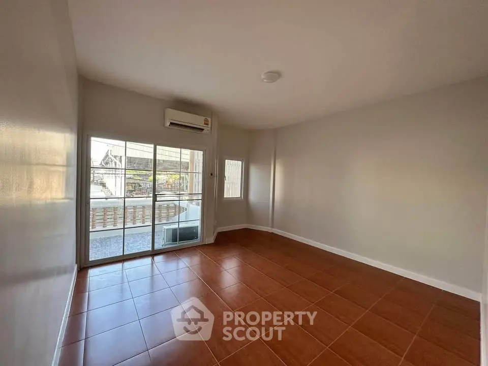 Spacious empty room with large windows and balcony access, featuring sleek tile flooring and neutral walls.
