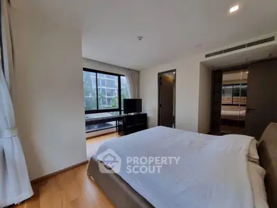 Spacious bedroom with large windows and modern decor in a luxury apartment.