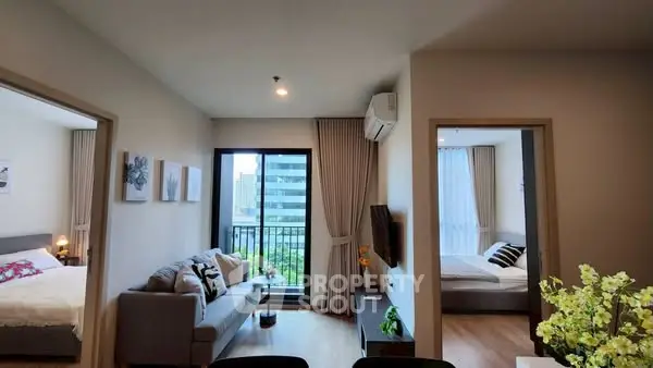 Modern apartment living room with balcony and two bedrooms, featuring stylish decor and natural light.