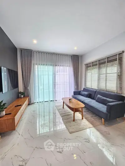 Modern living room with sleek furniture and large windows offering natural light.