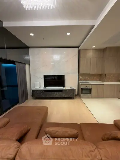 Modern living room with open kitchen, featuring sleek design and luxurious finishes.