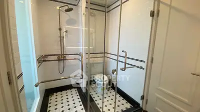 Elegant bathroom with glass shower enclosure and stylish black and white tile design.
