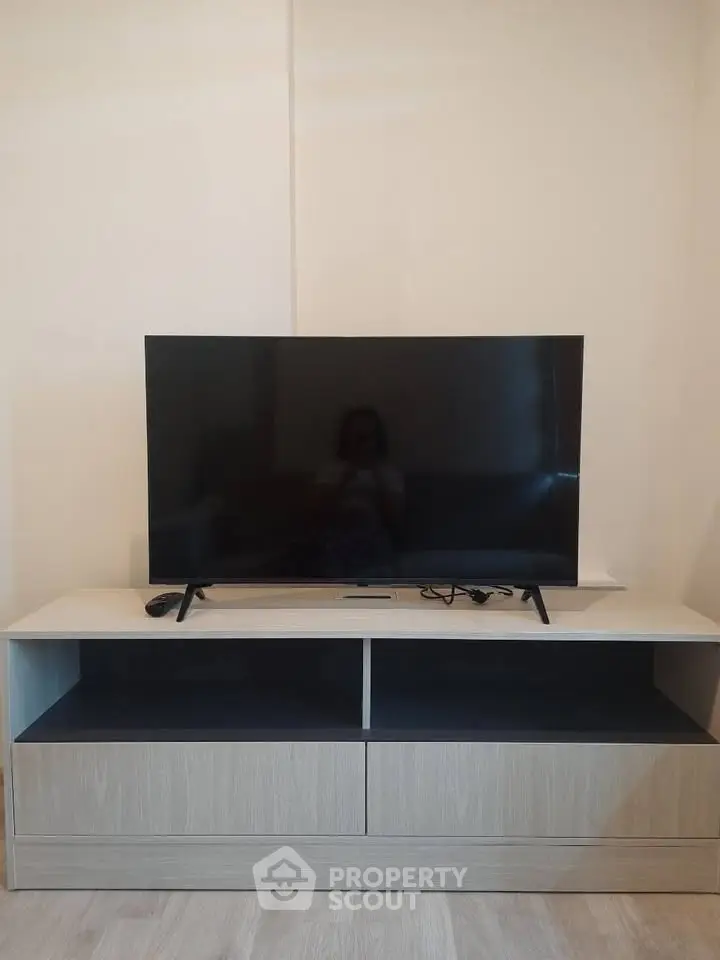 Modern living room with sleek TV on stylish wooden stand, perfect for entertainment.
