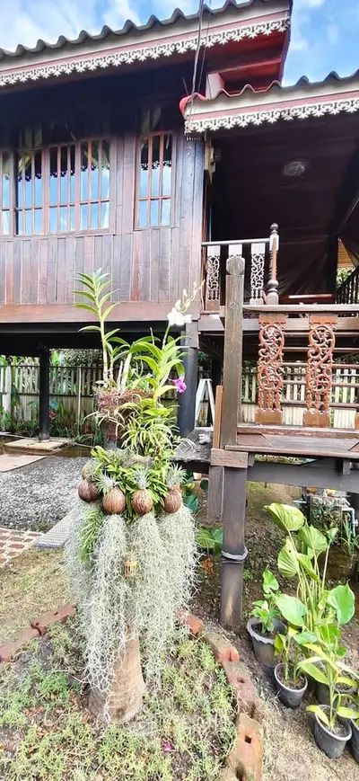 Charming traditional wooden house with intricate balcony railing and lush garden