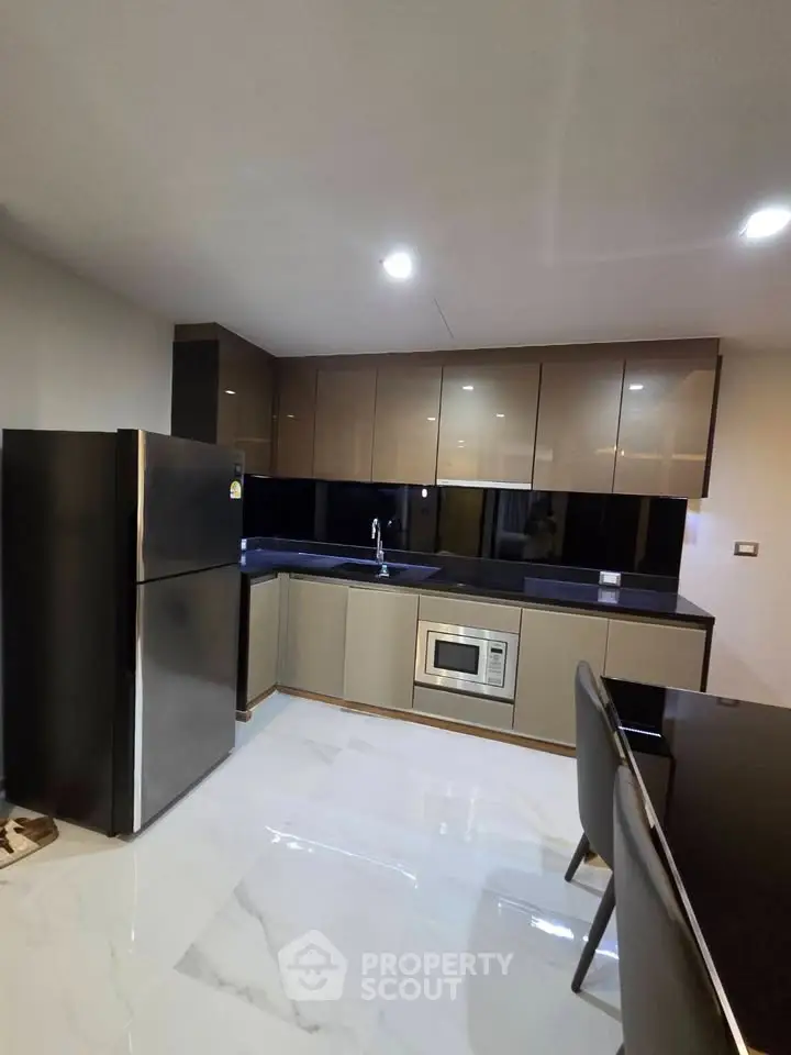 Modern kitchen with sleek cabinetry, stainless steel fridge, and built-in microwave in a stylish apartment.