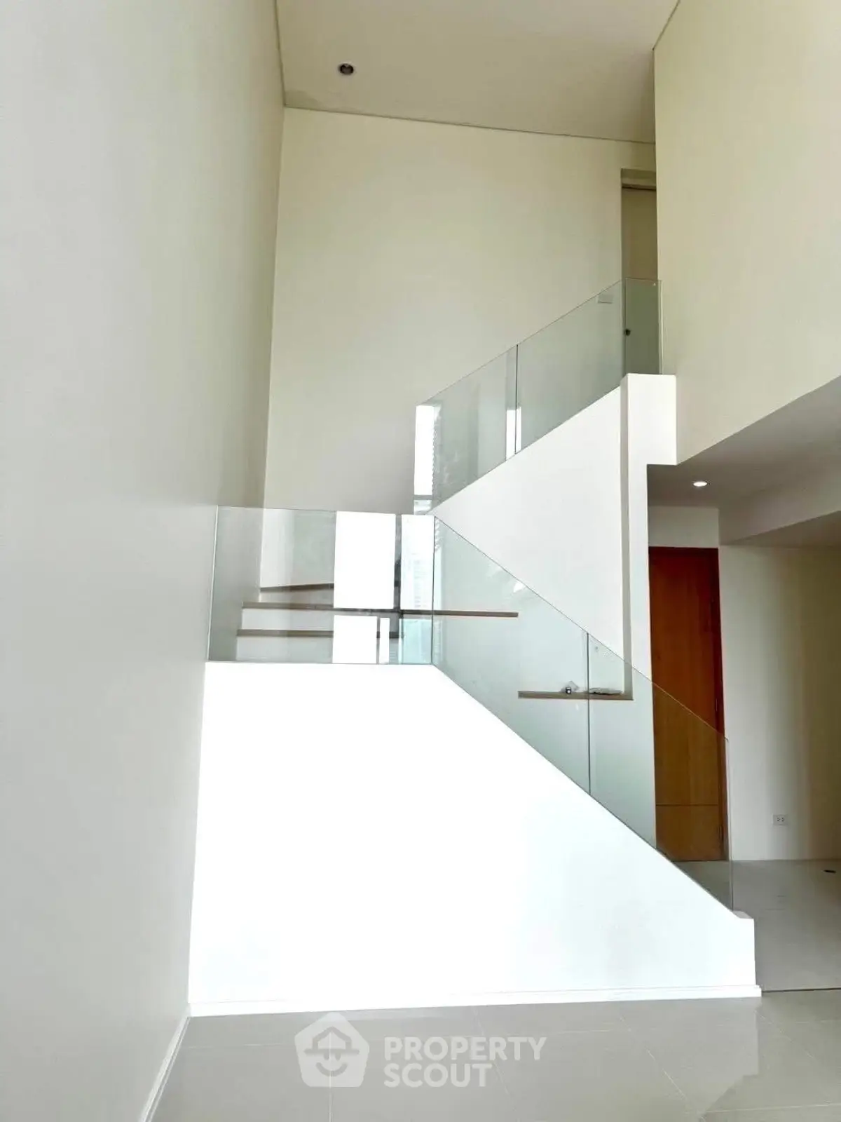 Modern minimalist staircase with glass railing in a bright interior space