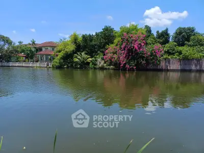 Scenic view of a serene lake with lush greenery and a charming house in the background.