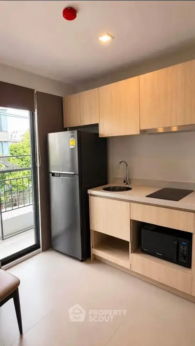 Modern kitchen with sleek cabinetry, built-in appliances, and balcony view in urban apartment.