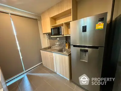 Modern kitchen with sleek appliances and wooden cabinetry in a cozy apartment setting.