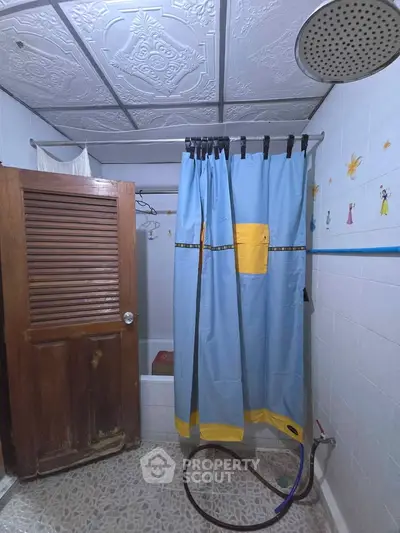 Cozy bathroom with shower curtain and wooden door, featuring decorative wall tiles.
