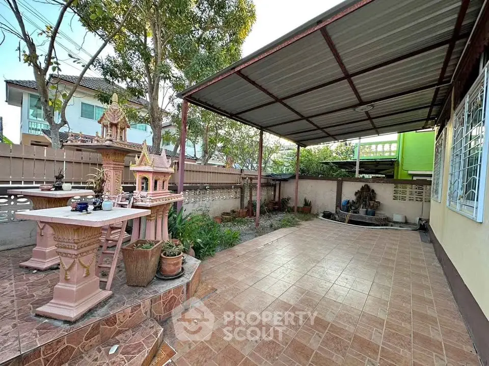 Spacious outdoor patio with tiled flooring and garden area in a serene residential setting.