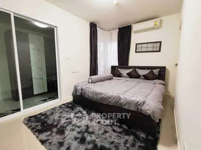 Modern bedroom with plush carpet and air conditioning in stylish apartment.