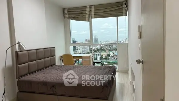 Modern bedroom with city view, featuring a cozy bed and study area.