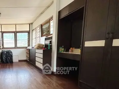 Spacious room with wooden flooring and ample storage in a well-lit interior.