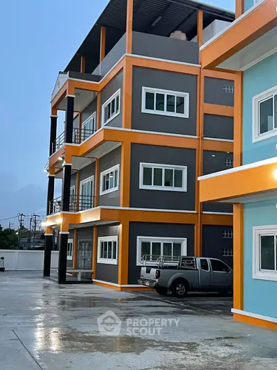 Modern multi-story building with vibrant colors and parking area