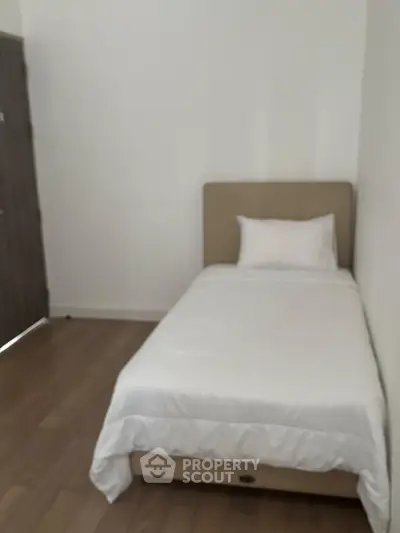Cozy minimalist bedroom with single bed and wooden flooring, perfect for a serene living space.