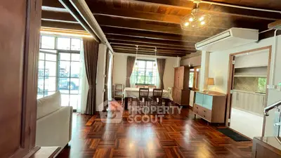 Spacious open-plan living and dining area with wooden flooring and modern lighting.