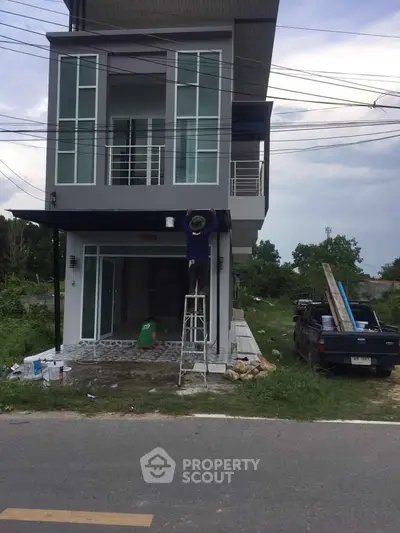 Modern two-story house under construction with a worker painting the exterior.