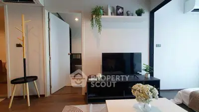 Modern living room with TV, plants, and stylish decor in a cozy apartment setting.