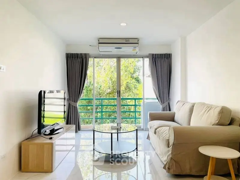 Bright and airy living room with modern furnishings and large windows overlooking greenery.