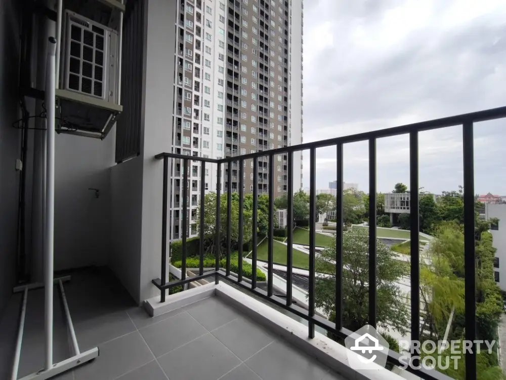 Modern high-rise apartment balcony with scenic city view and lush greenery.